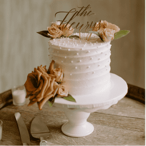 small cutting cake with pearls, fresh flowers and a peditle stand