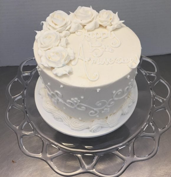 Anniversary Cake, An all white cake with buttercream roses on top and scrolls on the side