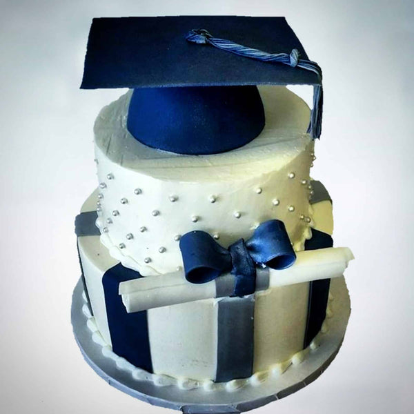 3 tier Graduation Cake, bottom tier with fondant vertical stripes, middle tier with dots and a graduation scroll wrapped in a bow, and the top tier an edible graduation hat