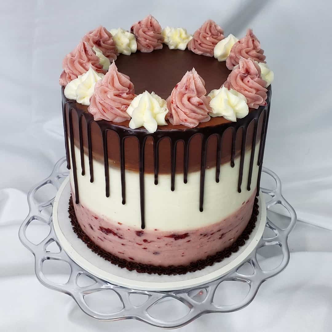neapolitan cake, with pink Champagne vanilla and chocolate layers, a ganache drip, and buttercream swirls on top