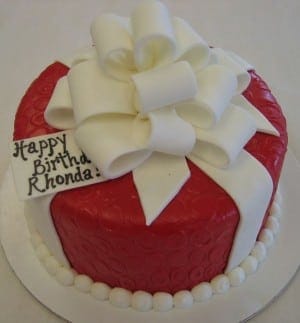 A red iced cake with a white multi loop bow on top