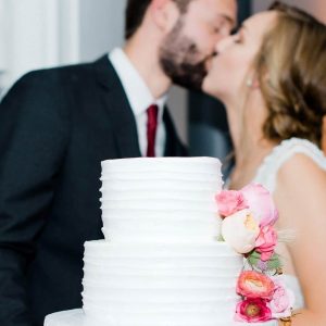 Couple kissing over wedding cake in Denver made by the best bakery in Denver